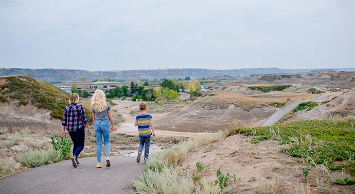 Three people walk on a badlands trail outside the Museum.