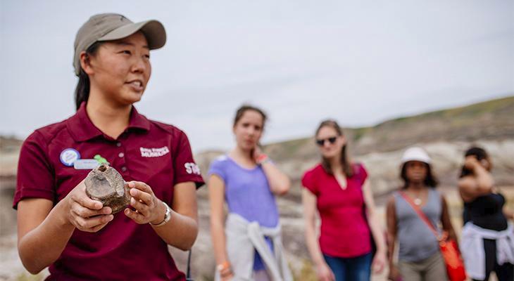 An educator shows a fossil to people in the badlands. 