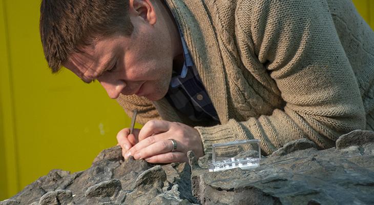 Caleb Brown uses a small tool to examine a fossil. 