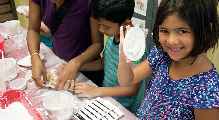 A young girl holds a plaster cast of a dinosaur claw. 