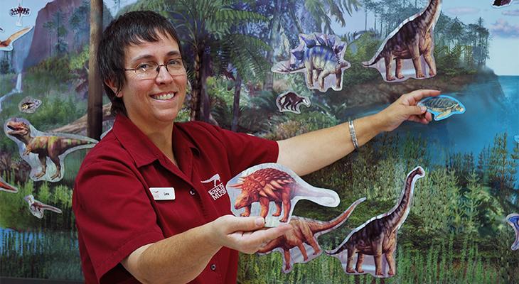 An educator holds dinosaur illustrations. 