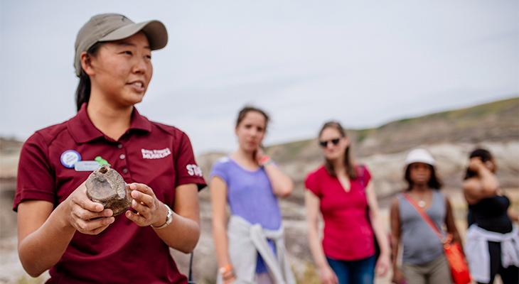 An educator shows a fossil to people in the badlands. 