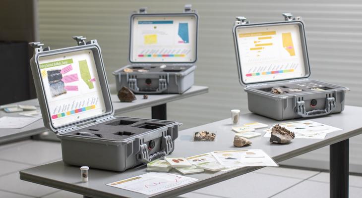 Three open briefcases on a table with papers and fossils nearby. 