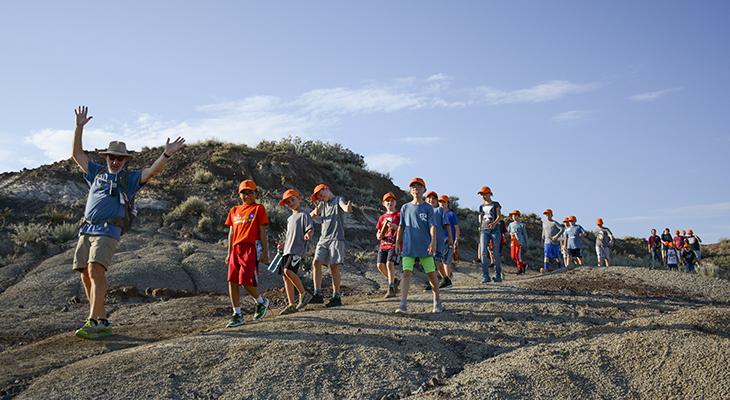 A camp counsellor leads children along a badlands trail. 